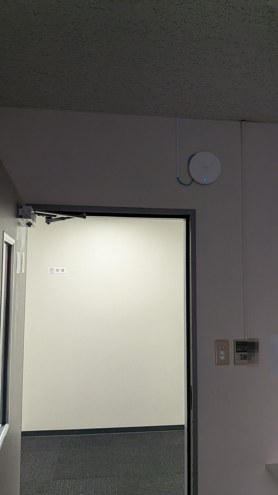 教室入口の上の壁に設置し、青いランプが点灯したアクセスポイント